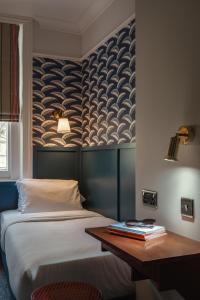 1 dormitorio con cama y mesa de madera en St. David's Hotels Paddington en Londres
