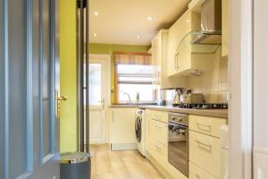 a kitchen with yellow walls and white cabinets at Gunn House in Grangemouth