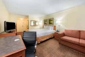 a hotel room with a bed and a couch at La Quinta by Wyndham Ft Lauderdale Cypress Creek in Fort Lauderdale