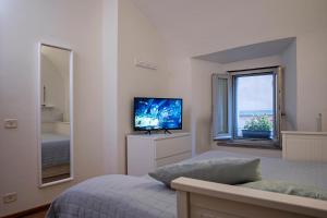 a white bedroom with a bed and a television at Casa Vèra Camelia Apartment in Orvieto