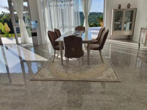 a dining room table and chairs in a room with windows at Villa Luiz Danneel: Vipingo Ridge in Mombasa