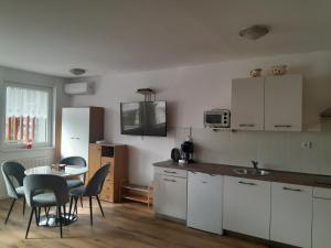 - une cuisine avec des placards blancs, une table et des chaises dans l'établissement Apartment Honey Bee with SAUNA, à Kobarid