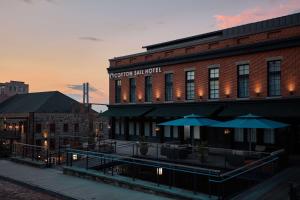 萨凡纳The Cotton Sail Hotel Savannah - Tapestry Collection by Hilton的前面有桌子和伞的建筑
