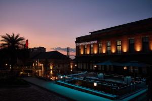 萨凡纳The Cotton Sail Hotel Savannah - Tapestry Collection by Hilton的一座建筑,在晚上前方有一个游泳池