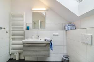 Baño blanco con lavabo y espejo en Haus Buche, en Hödingen