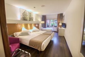 オビエドにあるGran Hotel Españaの大きなベッドとピンクの椅子が備わるホテルルームです。