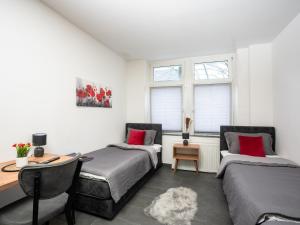 een slaapkamer met 2 bedden, een bureau en ramen bij SR24 - Stillvolles gemütliches Apartment 1 in Oer-Erkenschwick in Oer-Erkenschwick
