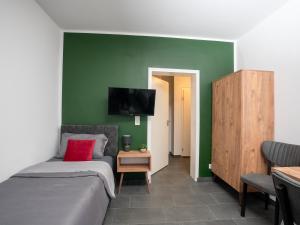 een slaapkamer met een bed en een tv aan een groene muur bij SR24 - Stillvolles gemütliches Apartment 1 in Oer-Erkenschwick in Oer-Erkenschwick