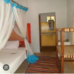 ein Schlafzimmer mit einem Bett mit einem blauen Vorhang in der Unterkunft Mangrove Beach Bungalows in Utende