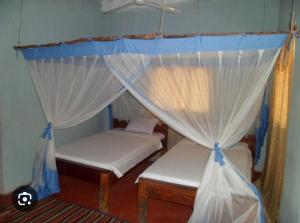 a bedroom with two beds and a canopy at Mangrove Beach Bungalows in Utende