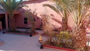 a courtyard with palm trees and a pink building at Gite d'étape nomade in Tajda