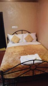 uma cama com lençóis brancos e almofadas num quarto em Gite d'étape nomade em Tajda