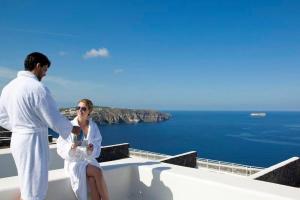 Ein Mann und eine Frau sitzen am Rande einer Badewanne in der Unterkunft Beautiful Santorini Villa - 2 Bedroom Villa - Panoramic Caldera Sea Views and Private Plunge Pool - Megalochori in Megalochori