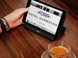 eine Person, die eine Tafel mit einer Kater-Website des Hotels aufhält in der Unterkunft Fora Hotel Hannover by Mercure in Hannover