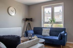 a living room with a blue couch and a clock at Perth House in Clydebank