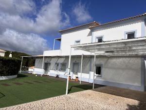 a white building with a grass yard in front of it at Villa Amêndoa in Loulé