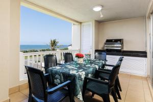 a dining room with a table and chairs and a balcony at Laguna La Crete 5 in Uvongo Beach