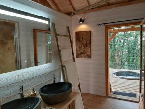 La salle de bains est pourvue d'un grand lavabo et d'une fenêtre. dans l'établissement Cabanes du Hérisson, cabanes perchées de standing avec spa, à Bonlieu