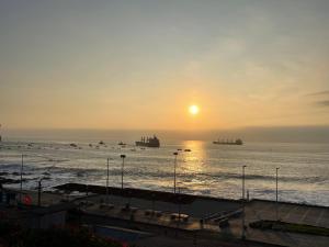 einen Sonnenuntergang über dem Meer mit Schiffen im Wasser in der Unterkunft Ubicación central cabaña frente al mar in Tocopilla
