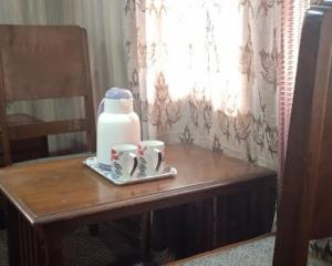 uma mesa de madeira com duas chávenas e um jarro. em Flora Cottage , Srinagar em Srinagar