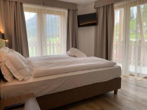 a bed sitting in a room with windows at Hotel Miravalle in Soraga