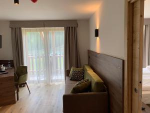 a living room with a couch and a bed and a window at Hotel Miravalle in Soraga