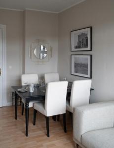 uma sala de jantar com uma mesa preta e cadeiras brancas em Modern, ruhig, gemütlich: 2 Zimmer Wohnung in bester Lage nahe Alster + Stadtpark em Hamburgo