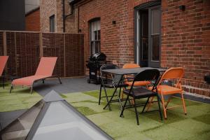 eine Terrasse mit Stühlen, einem Tisch und einem Grill in der Unterkunft Spacious Norwich Lanes Apartment with Roof Terrace in Norwich