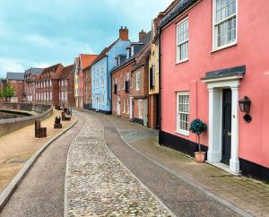 an empty street with colorful houses on the side at Stylish Quayside Apartment with River View in Norwich