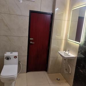 Hotel Mahamaya في Satna: حمام بباب احمر ومغسلة