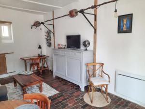 salon z telewizorem, stołem i krzesłami w obiekcie Gîte de Vernelle - Saint Pierre en Auge w mieście Bretteville-sur-Dives