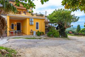 Una casa amarilla con un árbol delante. en Case Vacanze Castellana Iris en Sciacca