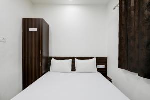 a bedroom with a white bed with a wooden headboard at OYO Hotel Karthik Palace in Bhopal