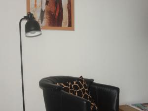 une lampe noire assise à côté d'un fauteuil en cuir noir dans l'établissement Grimm's Lodge, à Lörrach