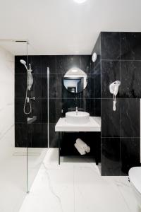 a black bathroom with a sink and a mirror at Lulu Apartments - Apartament FLORA z klimatyzacją - Solny Resort in Kołobrzeg