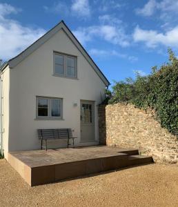 a white house with a bench in front of it at Stunning East Devon Cider Barn in Northleigh