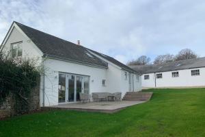 Stunning East Devon Cider Barn في Northleigh: بيت ابيض بطاوله وكراسي في ساحه