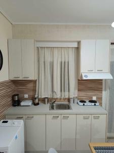 a small kitchen with a sink and a window at Lagadas Shiny apartments in Mytilini