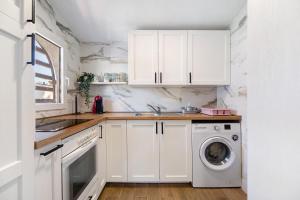 a kitchen with white cabinets and a washer and dryer at Spica in Novo Sancti Petri