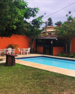 a swimming pool with tables and chairs next to a house at Pousada Bella Vida Geriba in Búzios