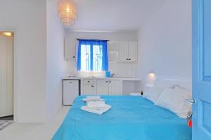 Habitación blanca con cama azul y ventana en Thalassopetra in Agia Kyriaki, en Agia Kiriaki Beach