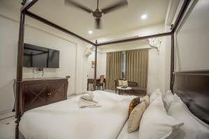 a bedroom with a large white bed with a television at ASHOK VILLA in Jaipur