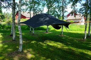 Une tare noire est suspendue entre deux arbres dans l'établissement Hannaksen tila - Tentsiles, à Korpo