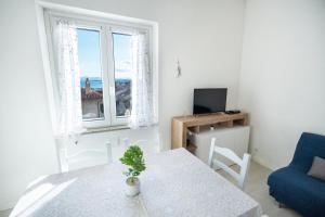 a white living room with a table and a blue chair at "Tramontana" vista mare - 300m dalla spiaggia in Golfo Aranci