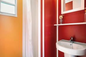 baño con lavabo y pared roja en Linda casita, en El Palmar
