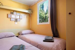 Duas camas num quarto com uma janela em Linda casita em El Palmar