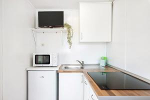 a white kitchen with a sink and a microwave at Linda casita in El Palmar +12 photos