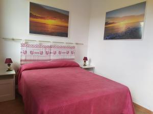 um quarto com uma cama com uma colcha rosa em Ajò Faci a Mari em Capoterra