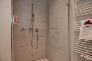 une douche avec une porte vitrée dans une salle de bain dans l'établissement Soloplan City Resort, à Kempten 34 autres photos