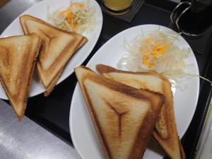 dos platos blancos de comida con sándwiches y ensalada de col en Hotel Forest, en Ōzu